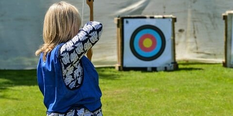 women at outdoor team building event participating in archery activity