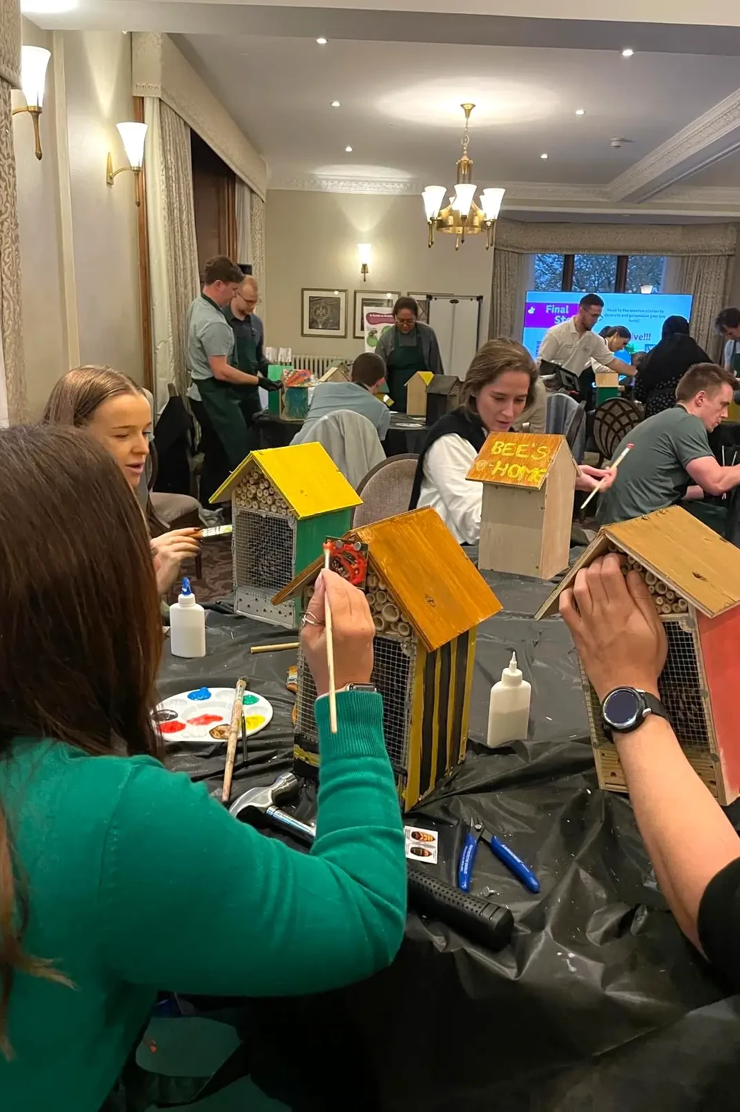 Team building participants painting bee hotels