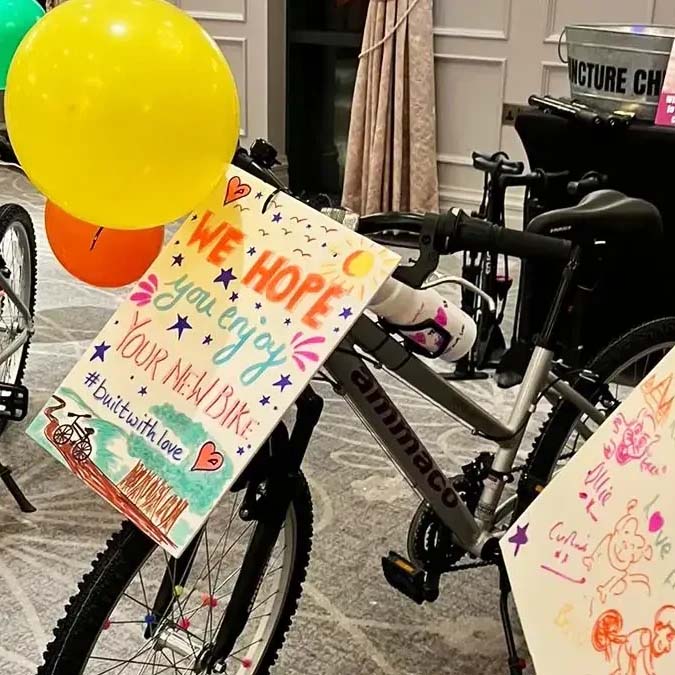 Black push bike decorated with balloons and a hand written sign