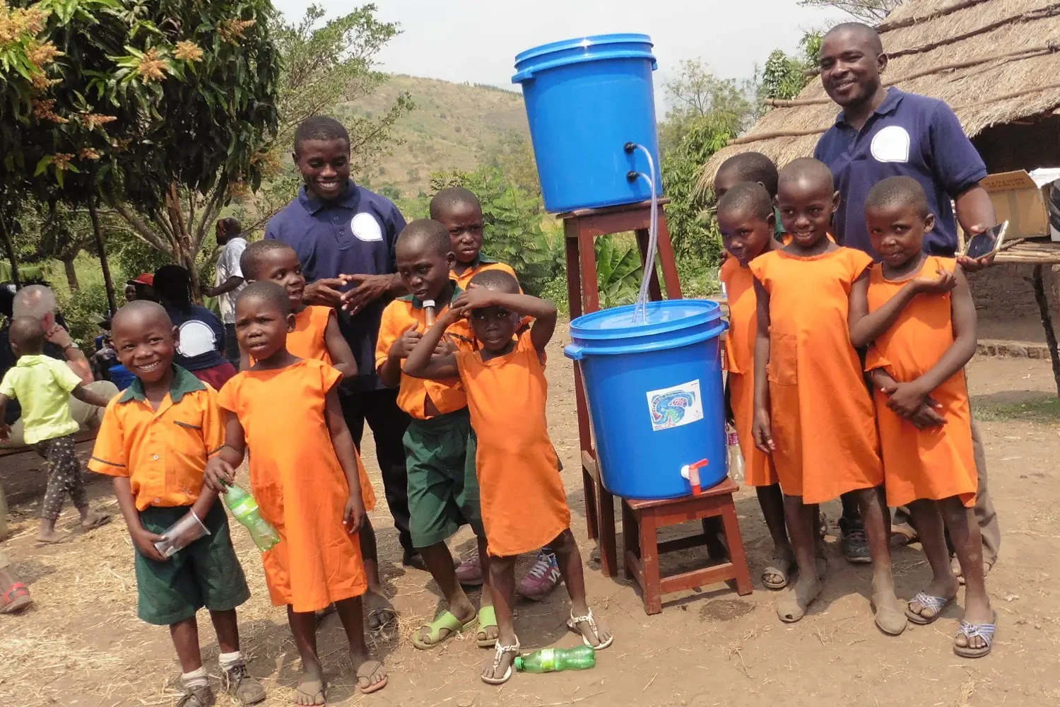 Children in bright orange tops with water filtarion system from the clean water project charity team building