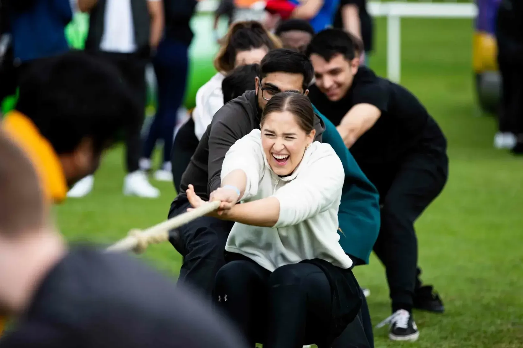people competing in tug of war on corporate fun day team building