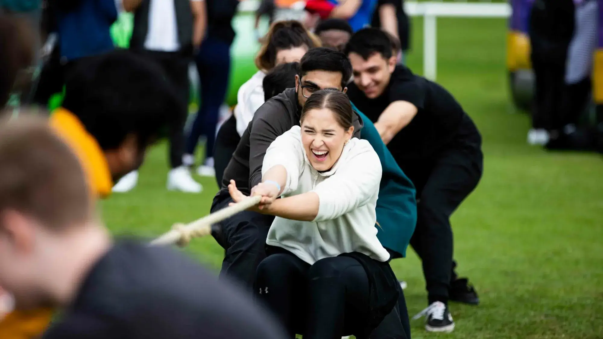 people competing in tug of war on corporate fun day team building