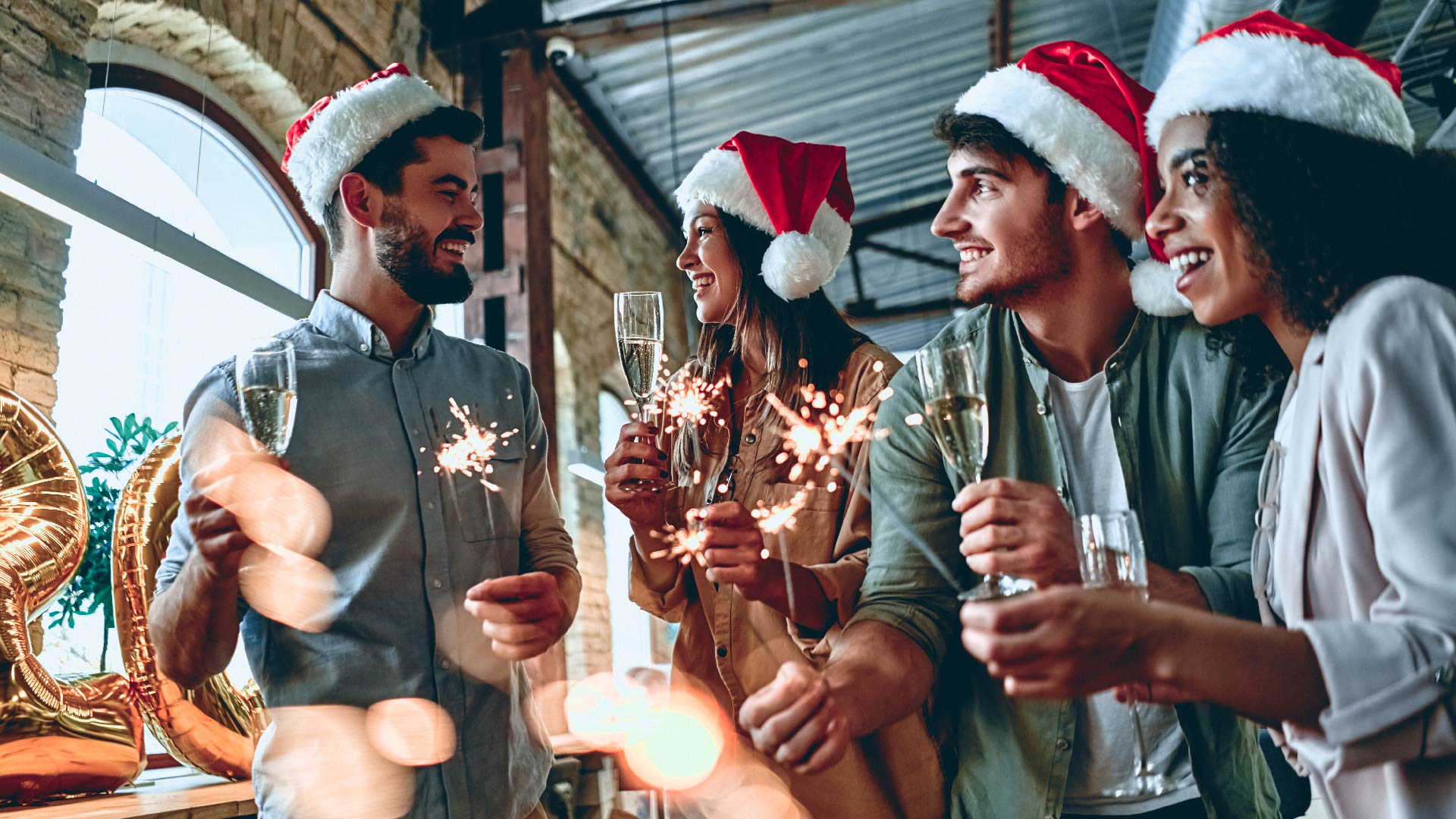 Group of people celebrating Christmas with a glass of Prosecco and a sparkler.