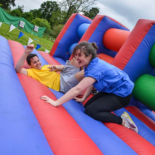 Two colleagues laughing on a giantn inflatable assault course