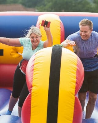 People having fun while competing in team building competition on inflatable course