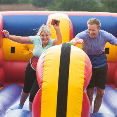 People having fun while competing in team building competition on inflatable course