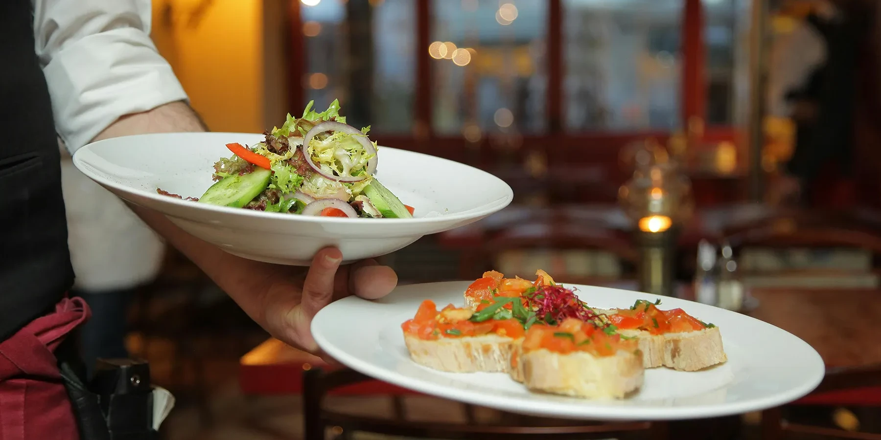 person holding plates with food at restaurant