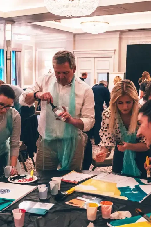 Group of people painting on canvas with water colours on Masterpiece creative team building event