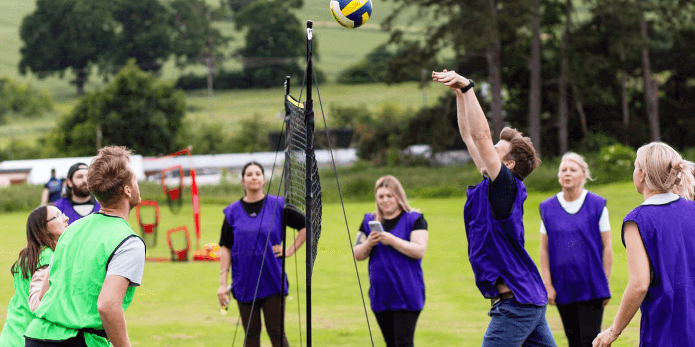 Teams participating in volleyball in outdoor team building event
