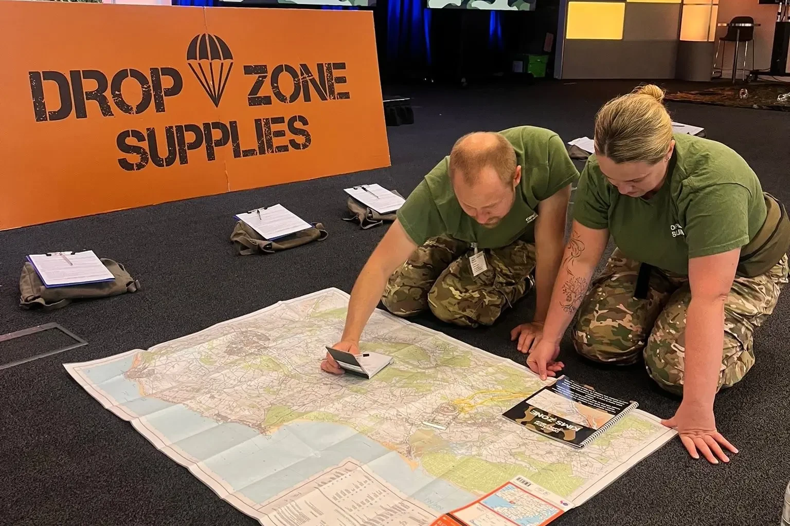 Operation supply drop participants in army outfits reading a map on the floor