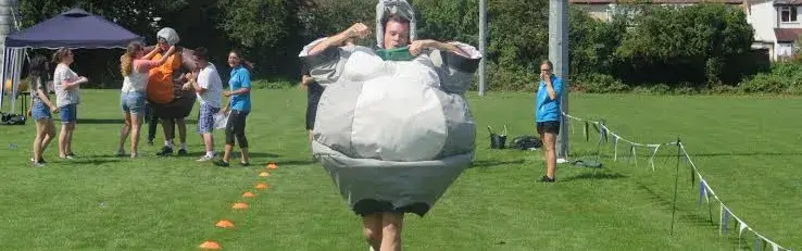 Person running in inflatable costume for team building sports race