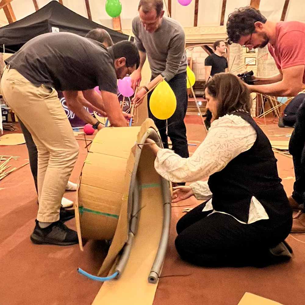 Colleagues building a rollercoaster out of cardboard, tubes and balloons