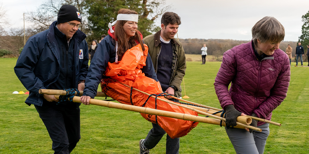 Women being carried by team in survivor island team building event for summer