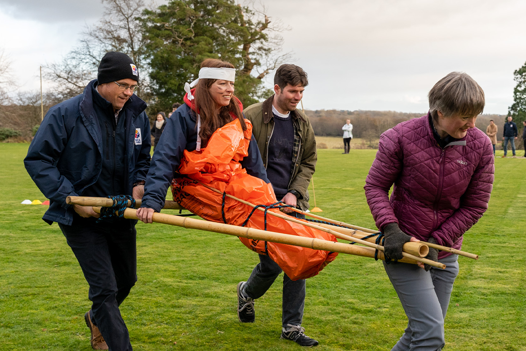 Women being carried by team in survivor island team building event for summer