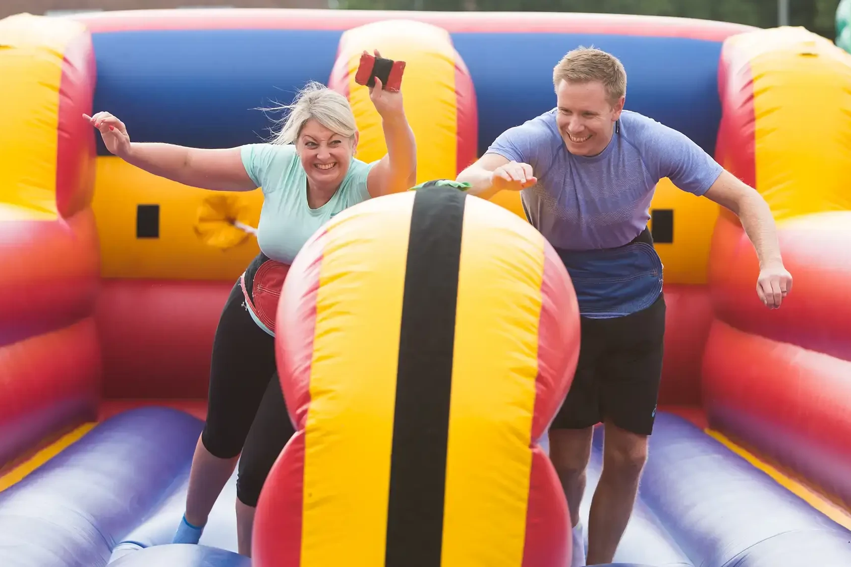 Employees participating in outdoor team building event on colourful inflatables.