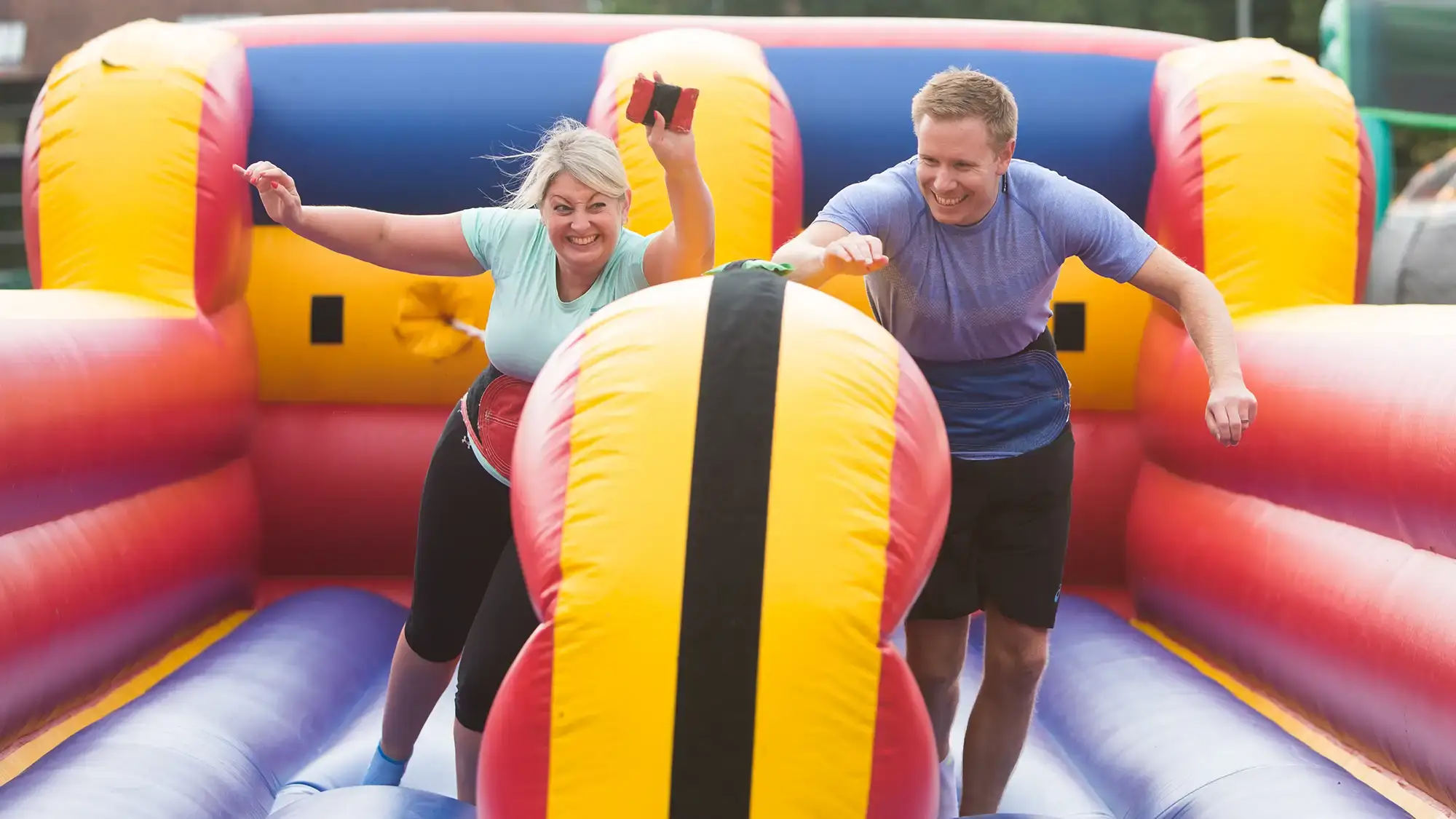 Employees participating in outdoor team building event on colourful inflatables.