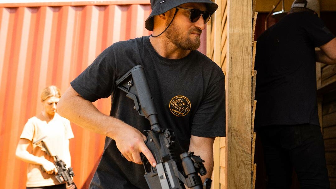 Man entering a container with a rifle.