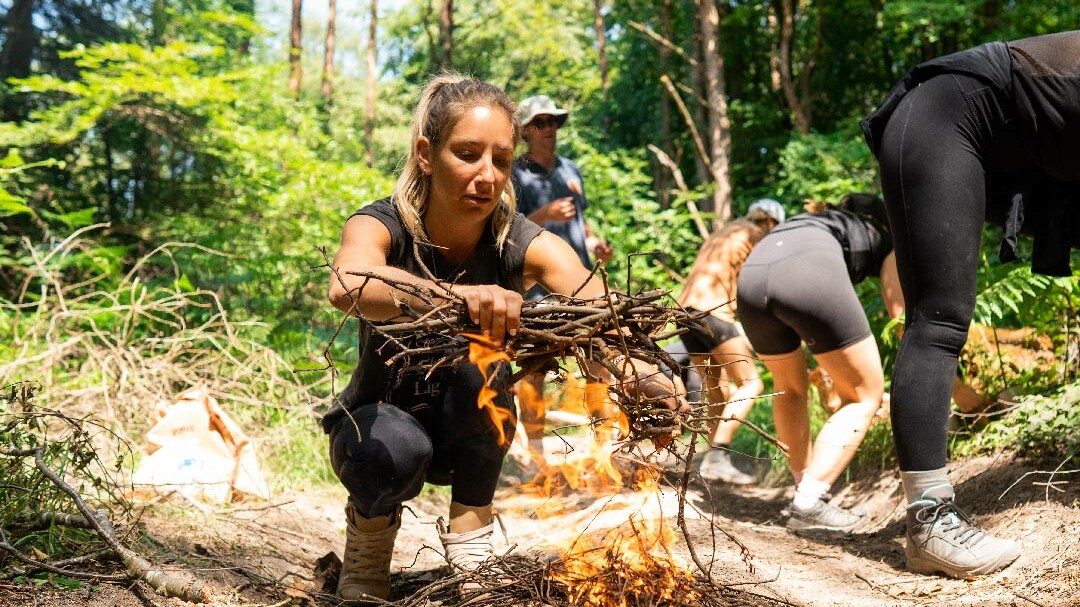 Woman lighting a fire in the forest.