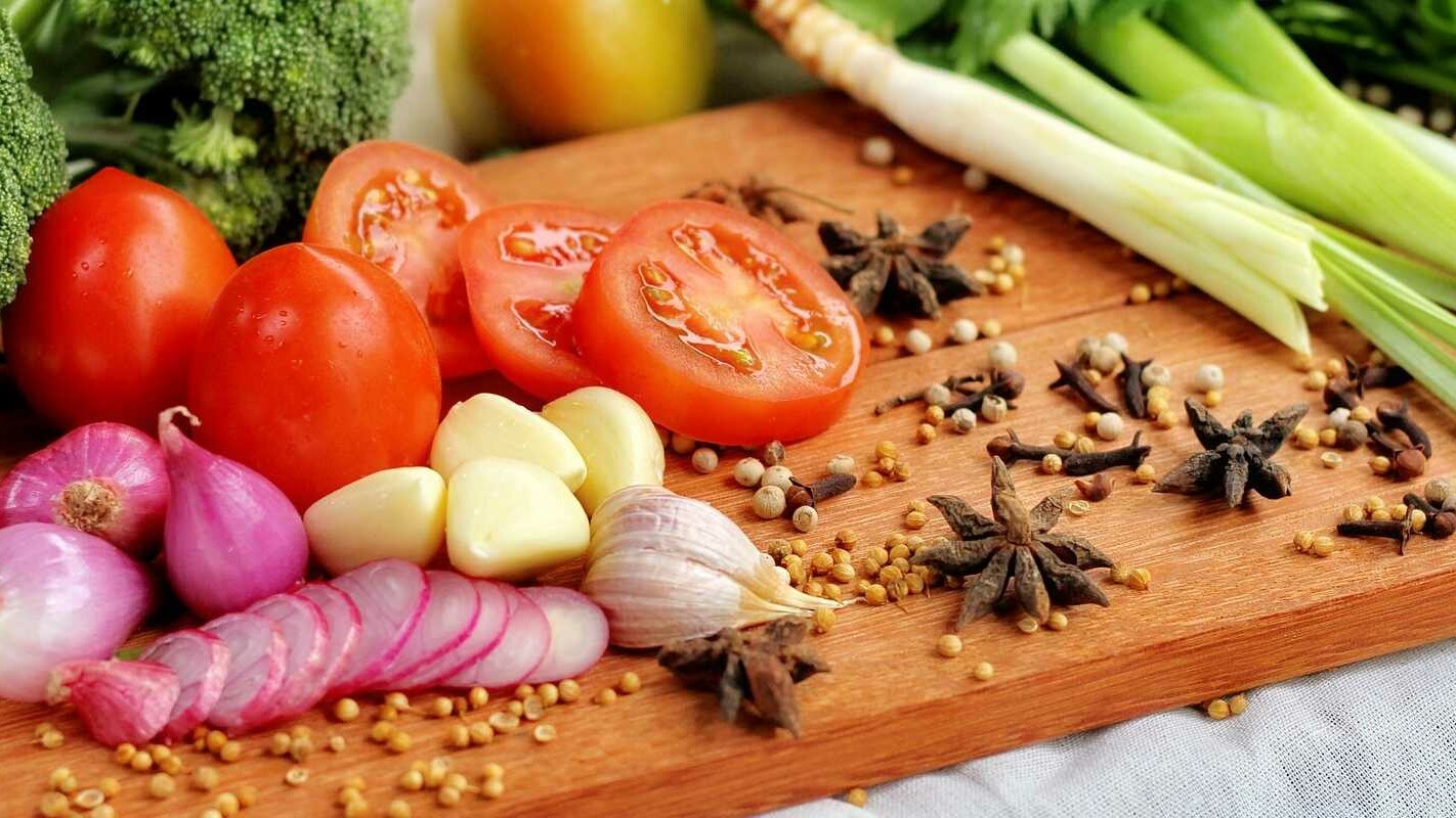 Close up of tomatos onions garlic and other ingredients on a chopping board