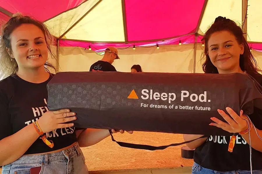 Women smiling holding sleep pod bag during charity team building