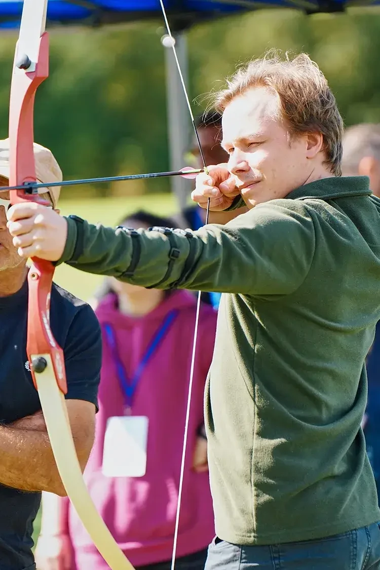 team building participant aiming for target in outdoor archery event