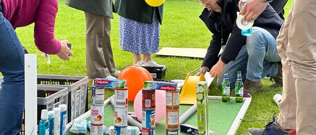 people on grass arranging boxes to build mini golf for charity team building