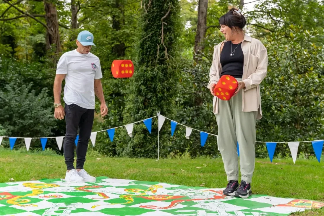 people playing giant board game with giant dice on green grass in compnay fun day