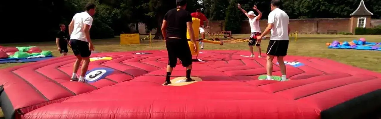 Team playing rounders on inflatable mat in outdoors team building sports day