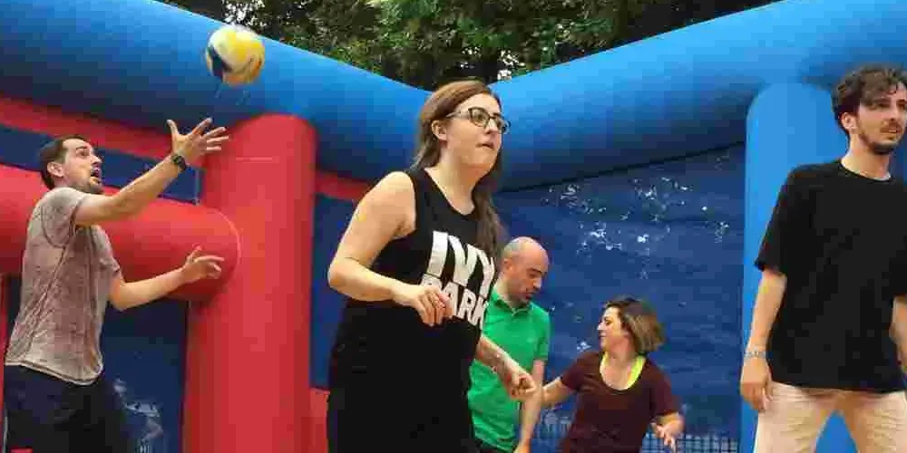 Team playing volleyball inside giant inflatable course