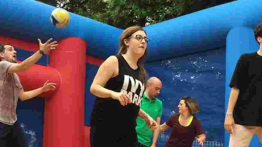Team playing volleyball inside giant inflatable course
