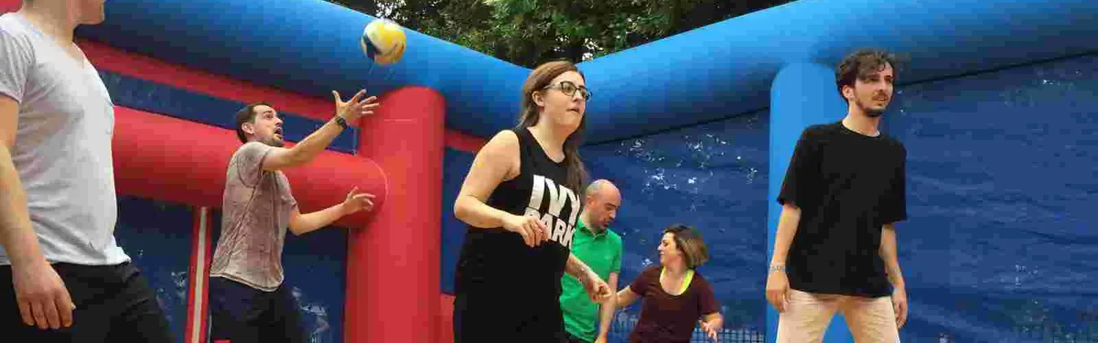 Team playing volleyball inside giant inflatable course