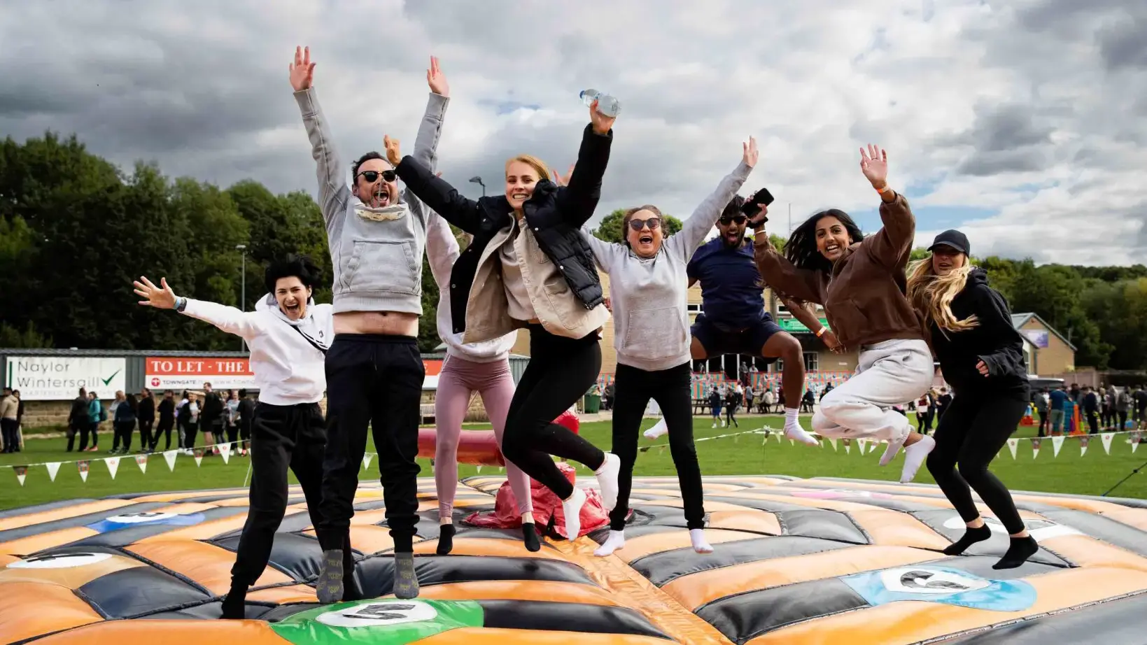 Group of employees jumping on inflatable in outdoor team building event