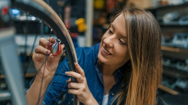 Lady fixing a bike wheel valve on charity team building event