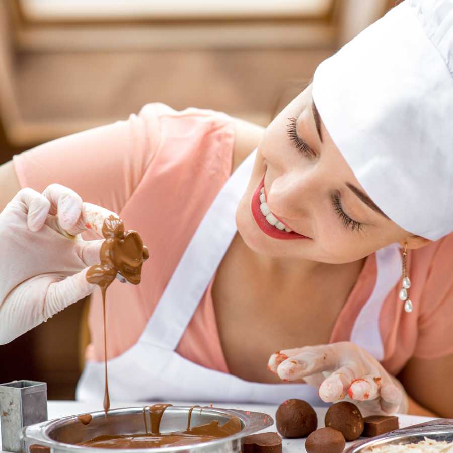 Lady dipping a chocolate into melted chocolate