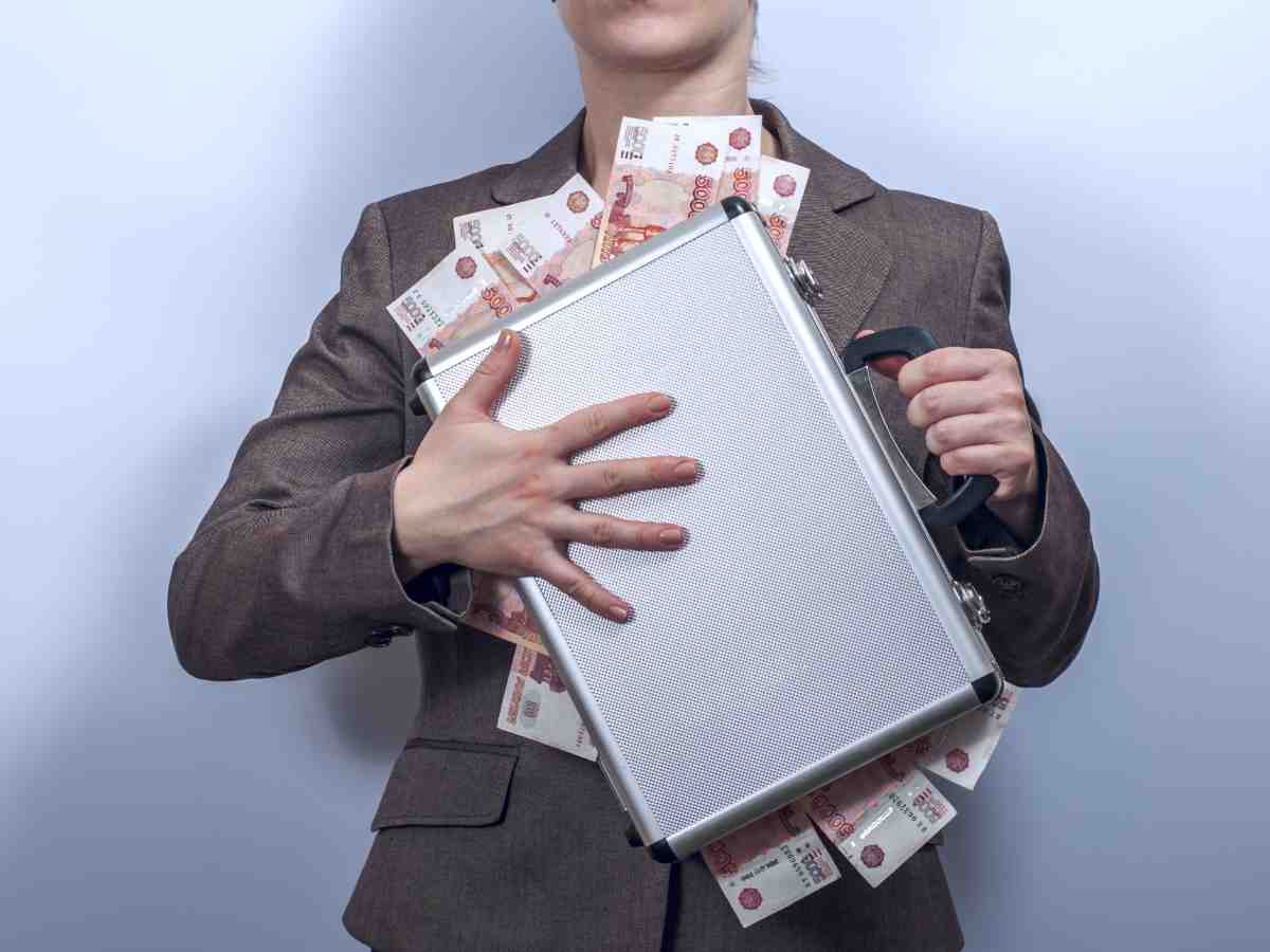 Lady holding closed briefcase with cash hanging out all sides