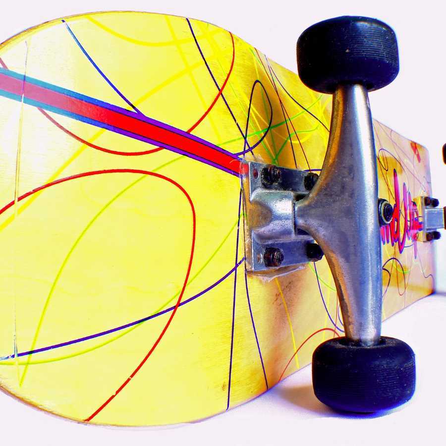 Close up of the bottom of a yellow skateboard with swirly line pattern