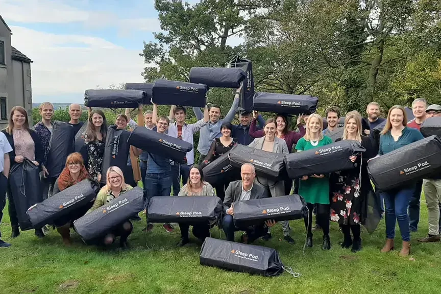 sleep pods charity team building participants holding sleep pod bags outdoors