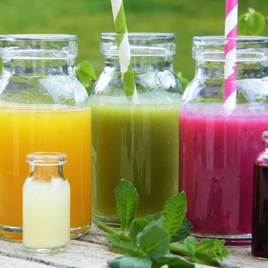 Yellow green and pink smoothies in glasses with straws