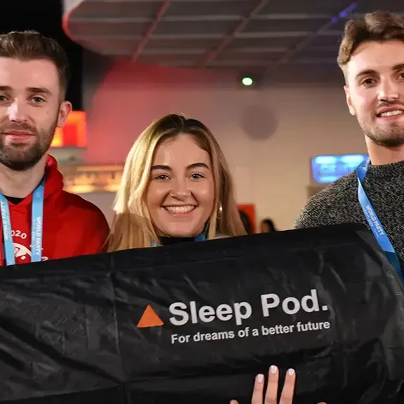 team holding sleep pod after constructing sleep pod in charity team building event
