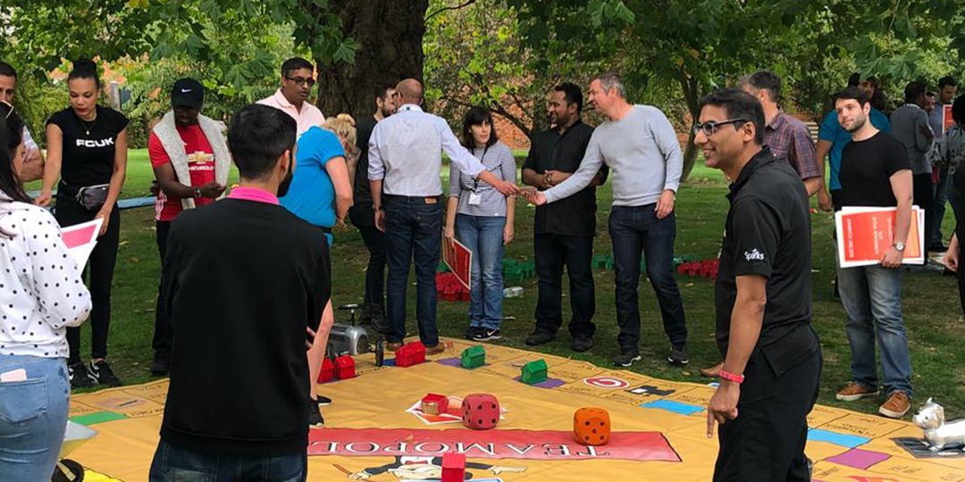 giant Monopoly set in park and players standing around the board