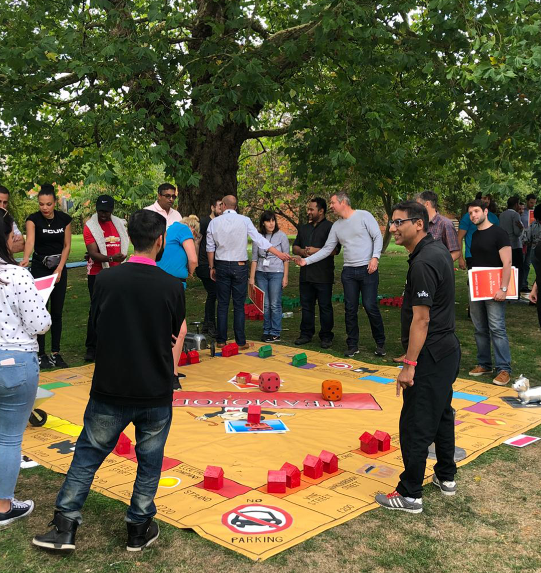 giant Monopoly set in park and players standing around the board