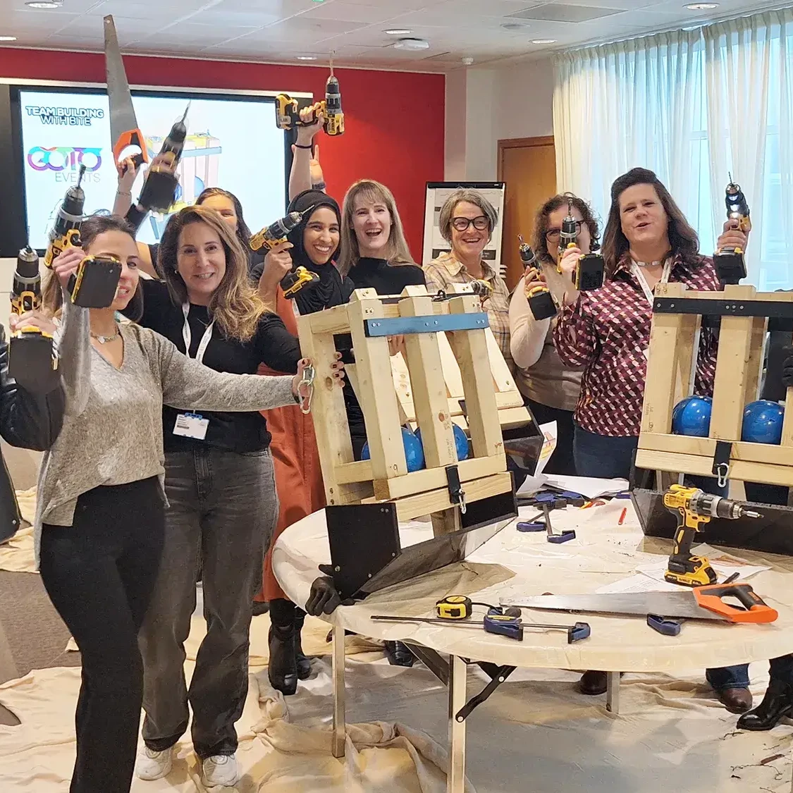 team participating in charity team building event building furniture for animals in shelter with drills